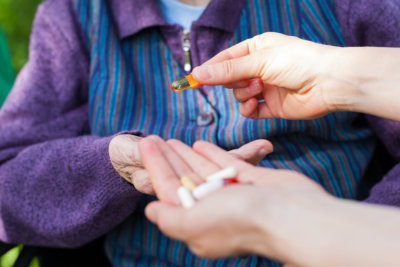 Close up picture of elderly disabled woman's hands receiving medical drugs from caregiver