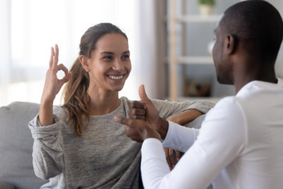 deaf and dumb couple using sign language for communication at home sit on sofa